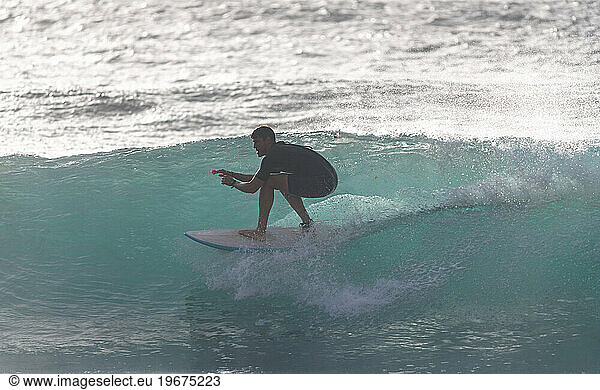 A young surfer crouching on a wave