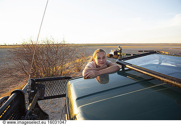 A young teenage girl on the roof of a safari jeep.