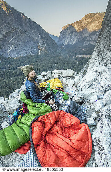 A young woman climber settles into her sleeping bag on Dinner Ledge