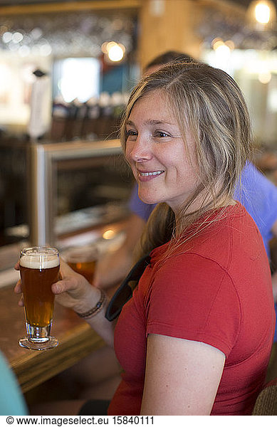 A young woman enjoys a beer with her friends at a bar in Oregon.