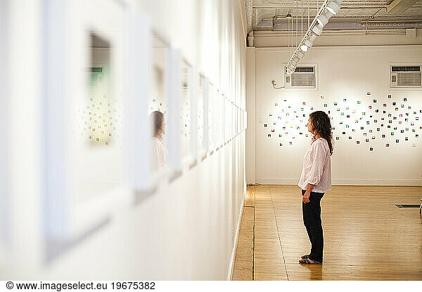 A young woman enjoys an art exhibit in a gallery.