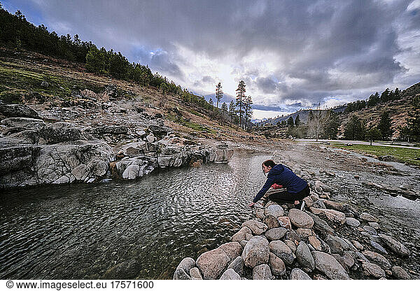 A young woman feeling the water temperature at Kirkham hot springs.