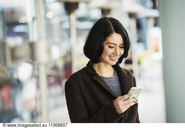 A young woman holding at a cellphone and smiling.