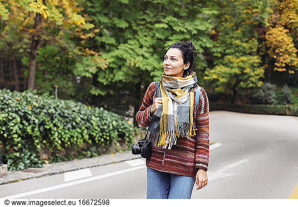 A young woman in a sweater in an autumn forest with a camera