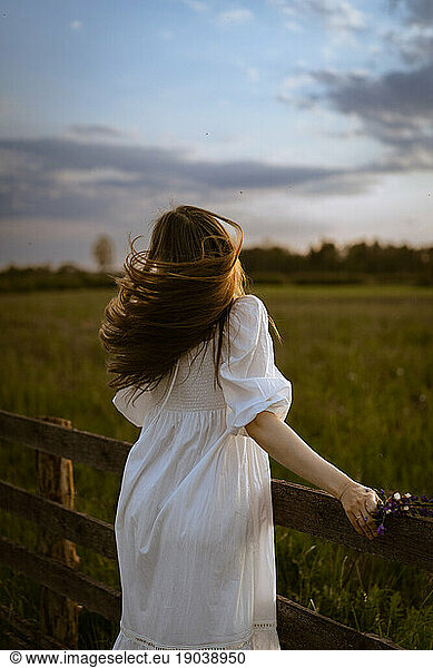 A young woman in a white sundress in the countryside.