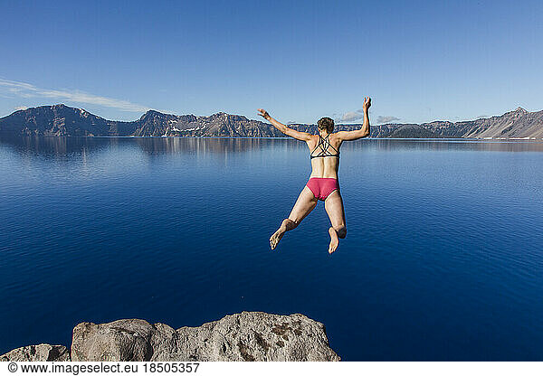 A young woman jumps in the cold  clear waters of Crater Lake.