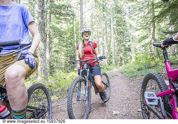 A young woman laughs while mountain biking with friends in Oregon.