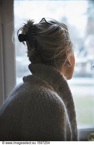 A young woman looking out of a window.