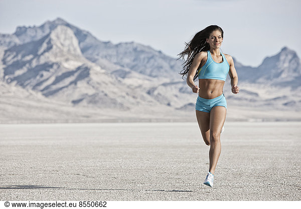 A young woman running through the landscape on the salt flats surface near Salt Lake city.