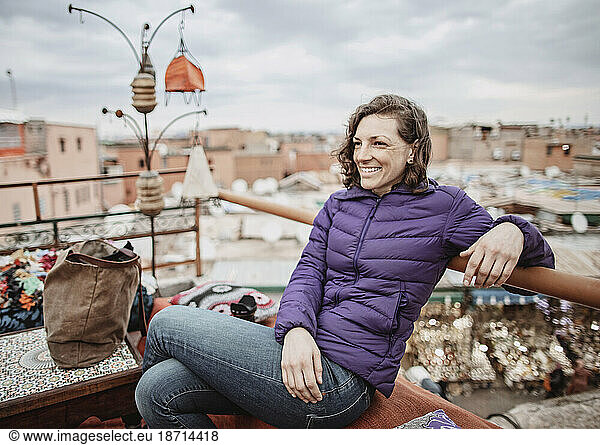 A young woman smiles while sitting on a rooftop in Marrakesh  Morocco