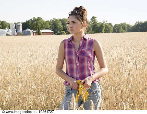 A young woman standing in a field of tall ripe corn.