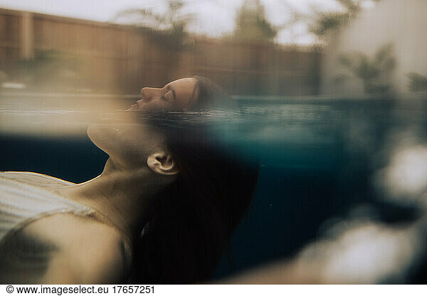 A young woman surfacing underwater in pool