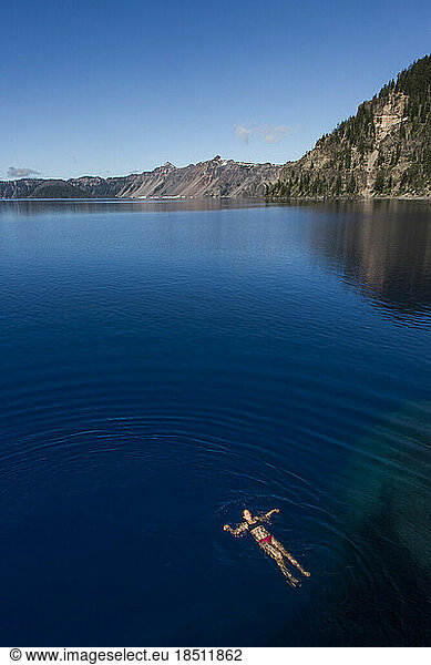 A young woman swims in the cold  clear waters of Crater Lake.