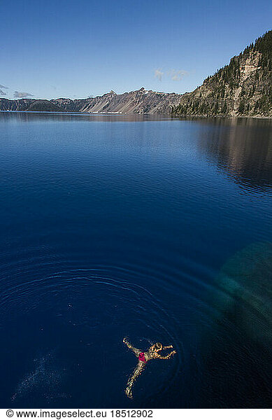 A young woman swims in the cold  clear waters of Crater Lake.