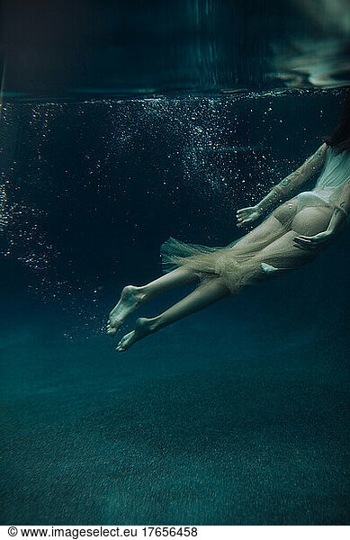 A young woman swims underwater on a gloomy day