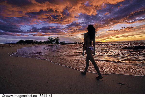 A young woman walks along Makalawena Beach on the Big Island of Hawaii