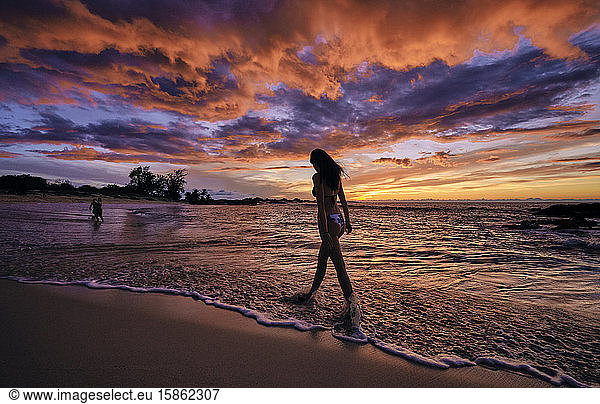 A young woman walks along Makalawena Beach on the Big Island of Hawaii