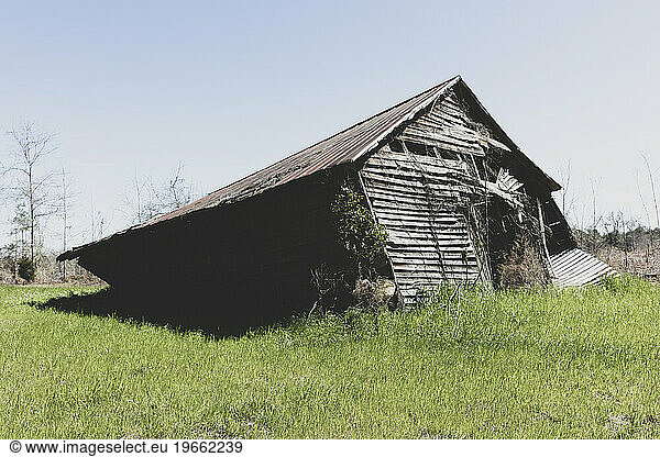 Abandoned barn leaning and near to collapse in a field.