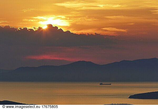 Abendhimmel orange  Sonnenuntergang  Schiff  Festland Berge im Hintergrund  Landzunge  graue Wolken  Abendhimmel rot  Westküste  Insel Andros  Kykladen  Griechenland  Europa