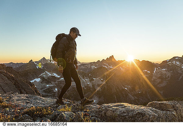 Abenteuerlustiger Mann beim Wandern entlang eines Bergrückens bei Sonnenuntergang.