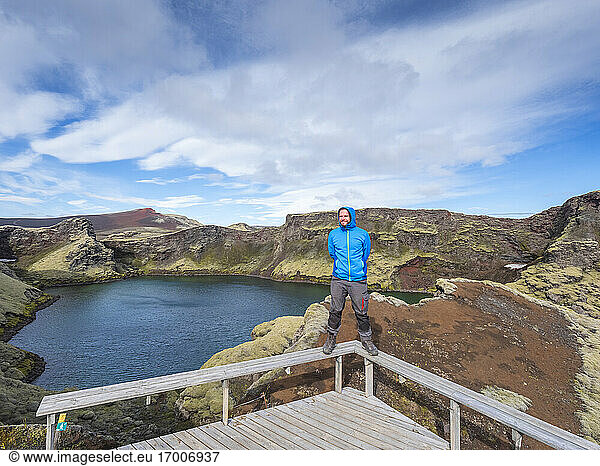 Abenteuerlustiger Mann steht auf einem Brückengeländer gegen den Himmel  Lakagigar  Island