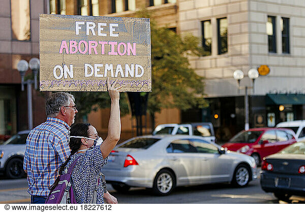 Abortion rights protesters stand by busy street holding a sign