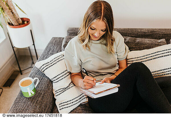 Above shot of woman writing in notebook from couch in living room