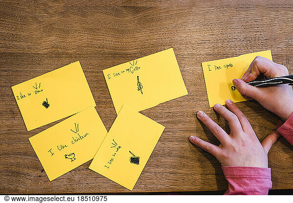 Above-view of hands of child drawing with pen on cards