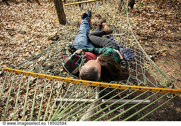 Above view of man and woman embracing lying down in hammock in fall