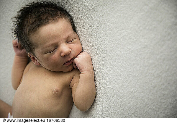 Above View of Newborn Boy With Lots of Hair Laying on Back on White