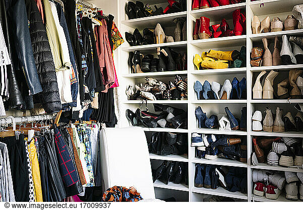 Abundance of footwear and clothes in wardrobe at home
