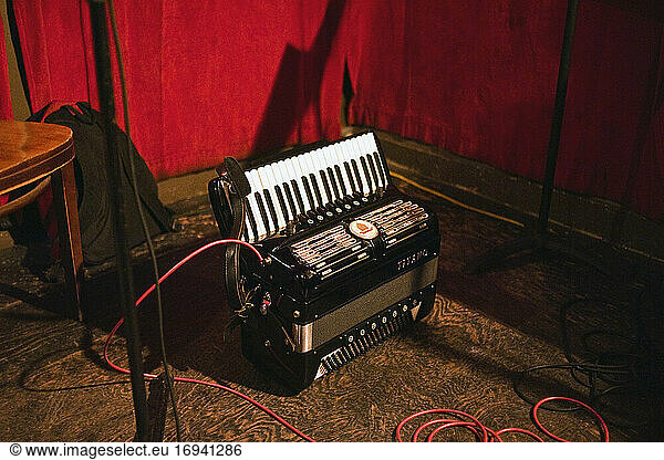 Accordion plugged in on floor of performance venue.