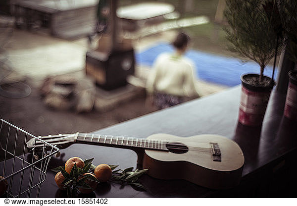 Acoustic Guitar lays on table with fresh picked fruit above fire place