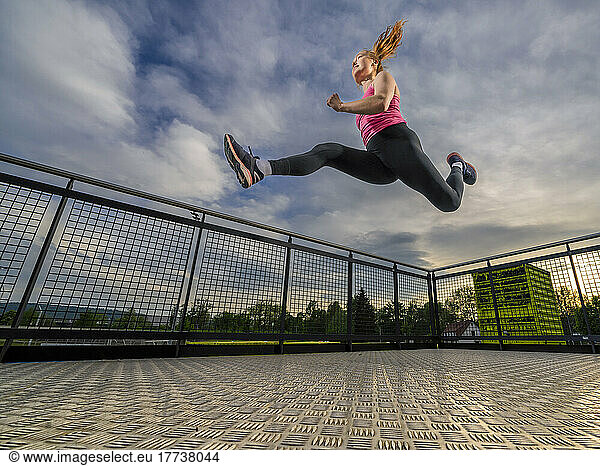 Active athlete jumping in sports park at sunset