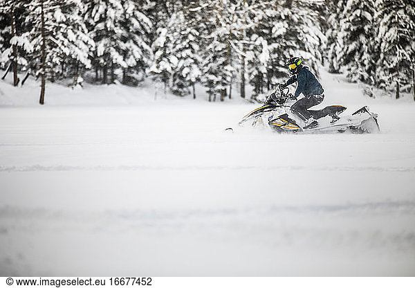 active man snowmobiling through deep snow during weekend getaway.
