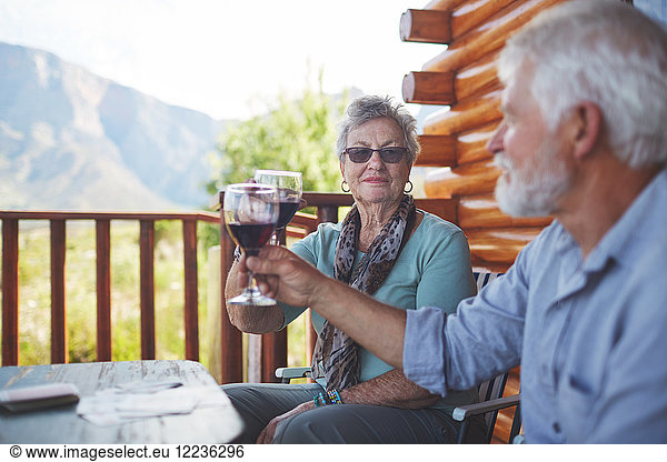 Active senior couple toasting red wine glasses on balcony