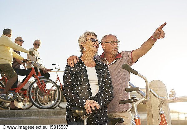 Active senior couple tourists with bicycles looking at view