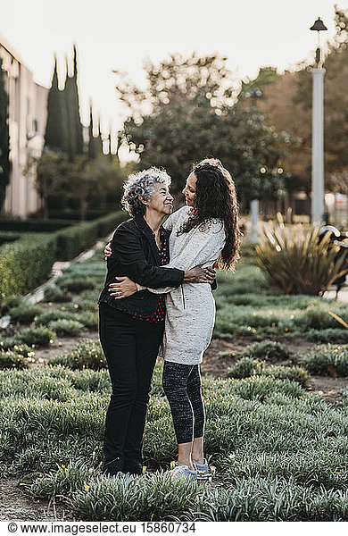 Active senior woman and adult daughter embracing each other outside