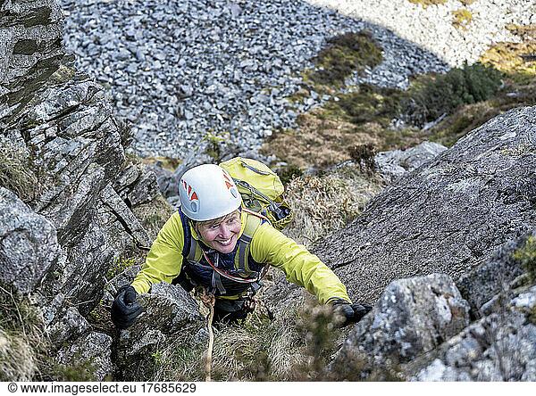 Active senior woman climbing rocky mountain