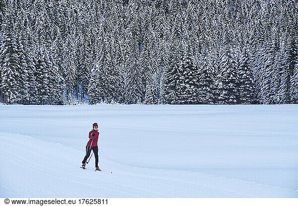 Active senior woman in ski wear skiing at winter forest on vacation