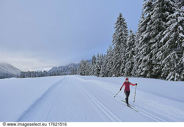 Active senior woman skiing in winter forest
