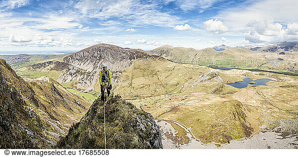 Active senior woman standing on top of rocky mountain peak