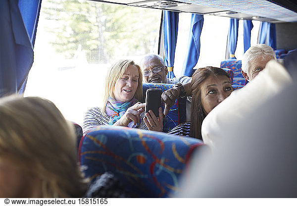 Active senior women tourists using smart phone on tour bus