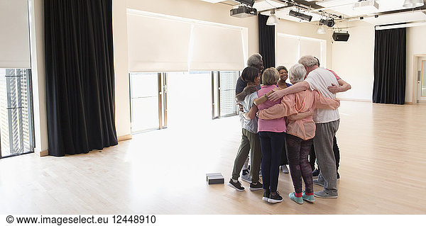 Active seniors bonding  hugging in circle in exercise studio