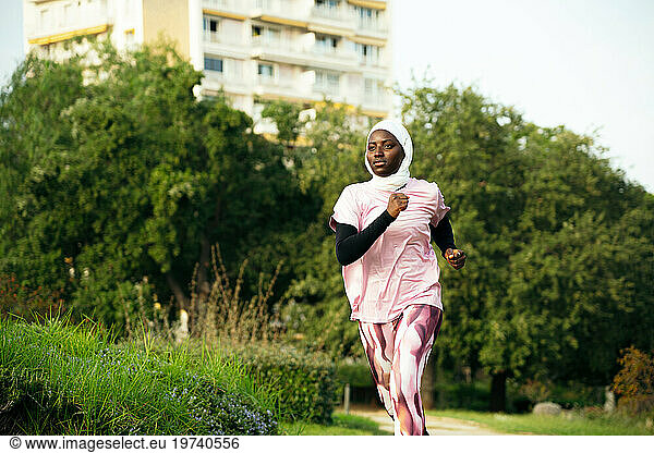 Active young woman wearing hijab running in park
