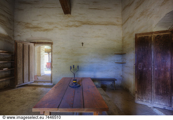 Adobe room in historic mission with wooden table and heavy wooden doors  Soldier's quarters at Mission La Purisima State Historic Park  Lompoc  California  Founded in 1787  the eleventh mission of the twenty-one Spanish Missions established in California