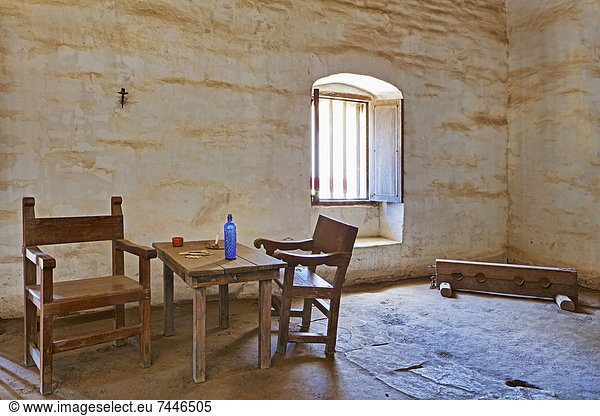 Adobe walled room with rough hewn table and chairs  card game in progress  and stocks for human punishment at Mission La Purisima State Historic Park  Lompoc  California  Founded in 1787  the eleventh mission of the twenty-one Spanish Missions established in California