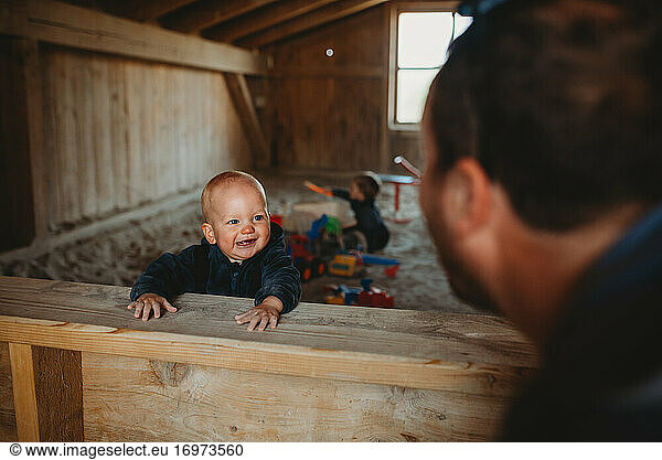 Adorable boy smiling at dad in an outdoor roofed sandbox in winter