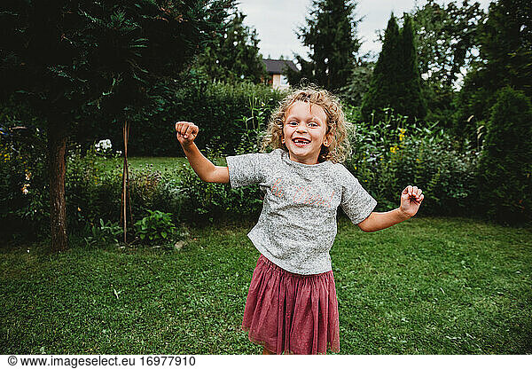 Adorable girl smiling and jumping in garden missing two front teeth
