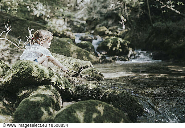 Adorable little girl playing the river in summer  with a cap and shorts.